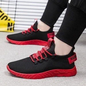 Black and red sneakers worn by a person on a blurred background