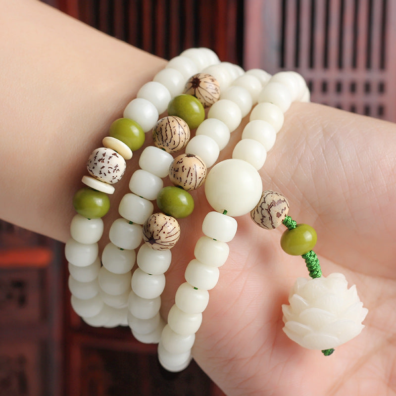 Close-up of a hand wearing multiple beaded bracelets with a blurred background