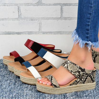 Row of espadrille sandals with different strap colors against a brick wall background.