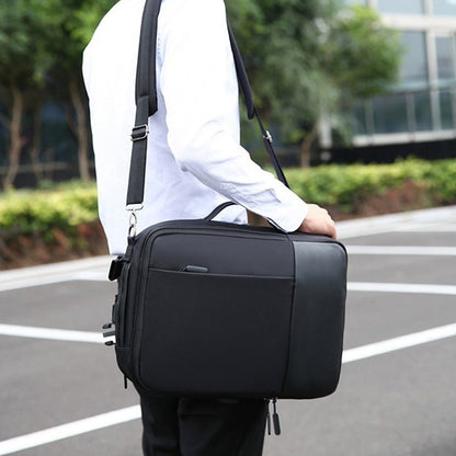 Person holding a black briefcase outdoors with blurred background
