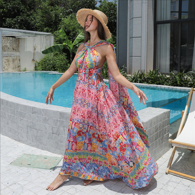 Woman in a colorful floral dress and hat standing by a poolside.