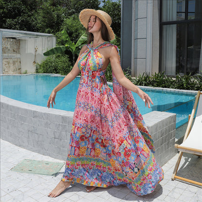 Woman in a colorful floral dress and hat standing by a poolside.