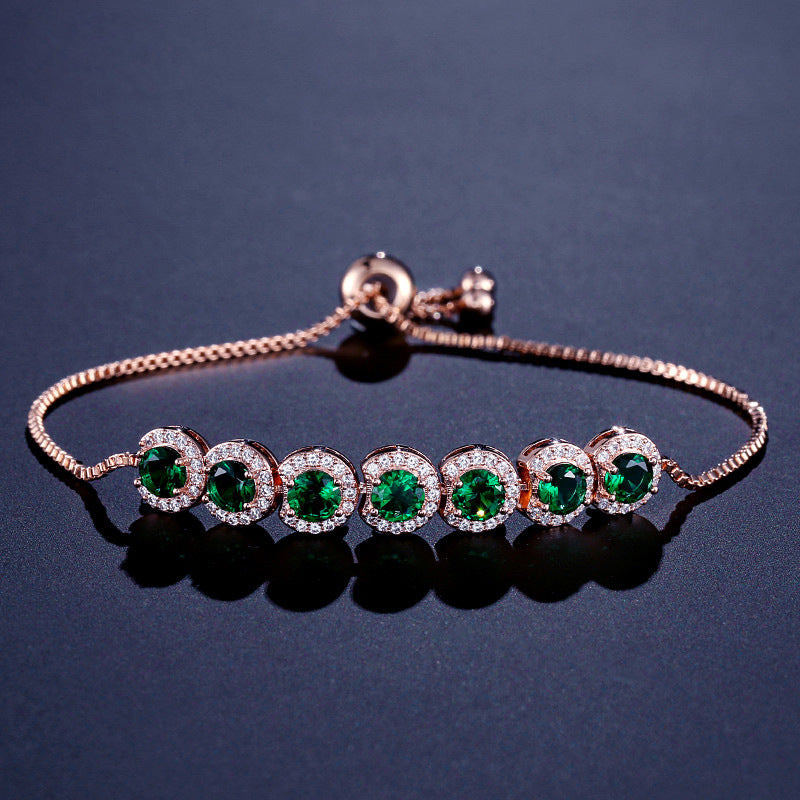 Rose gold bracelet with green gemstones on a dark background