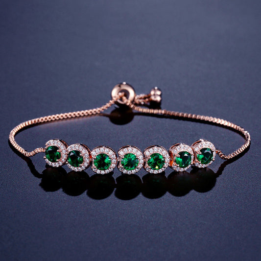 Rose gold bracelet with green gemstones on a dark background