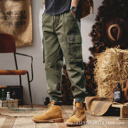 Person wearing green cargo pants and tan boots in a rustic setting with hay and wooden elements.