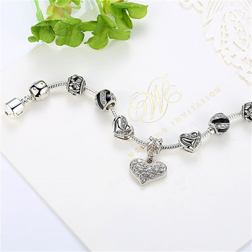 Silver bracelet with heart charm on a white card with gold text