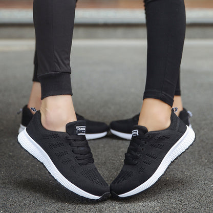 Black running shoes with white soles worn by a person on a blurred background