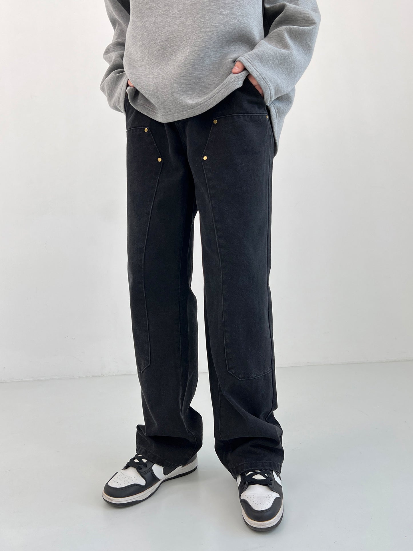 Person wearing black pants and a gray sweatshirt on a white background
