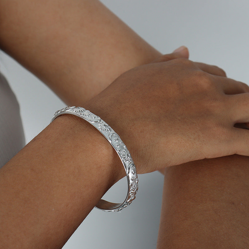 Silver bracelet on a wrist with a plain background