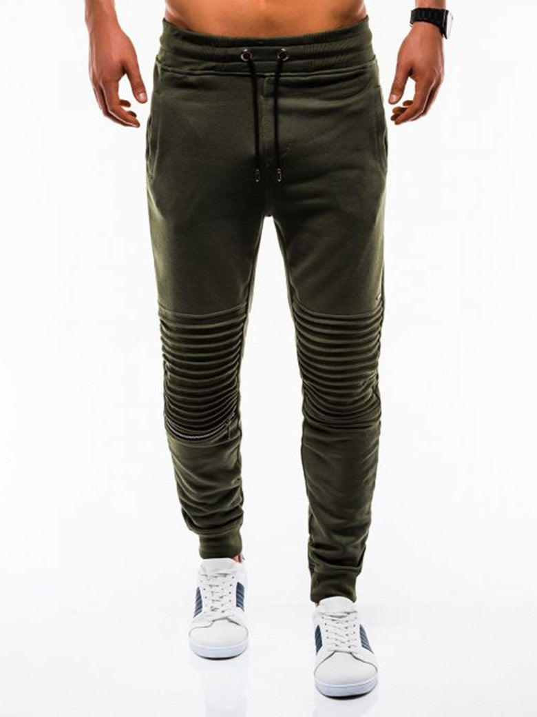 Green jogger pants worn by a person on a white background