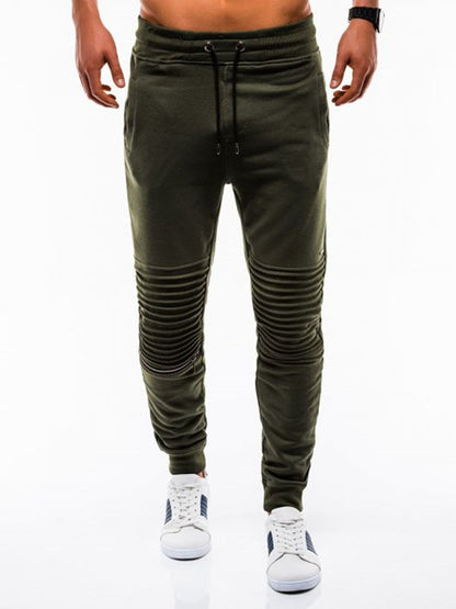 Green jogger pants worn by a person on a white background