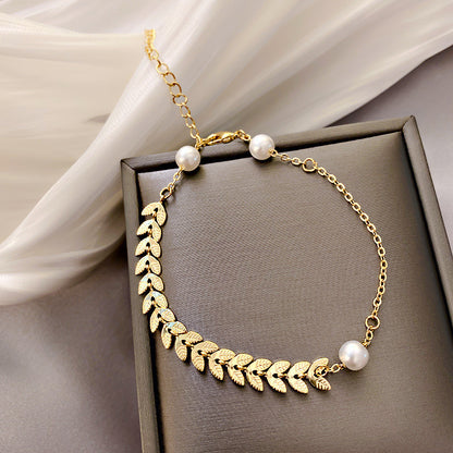 Gold necklace with leaf designs and pearls on a brown box