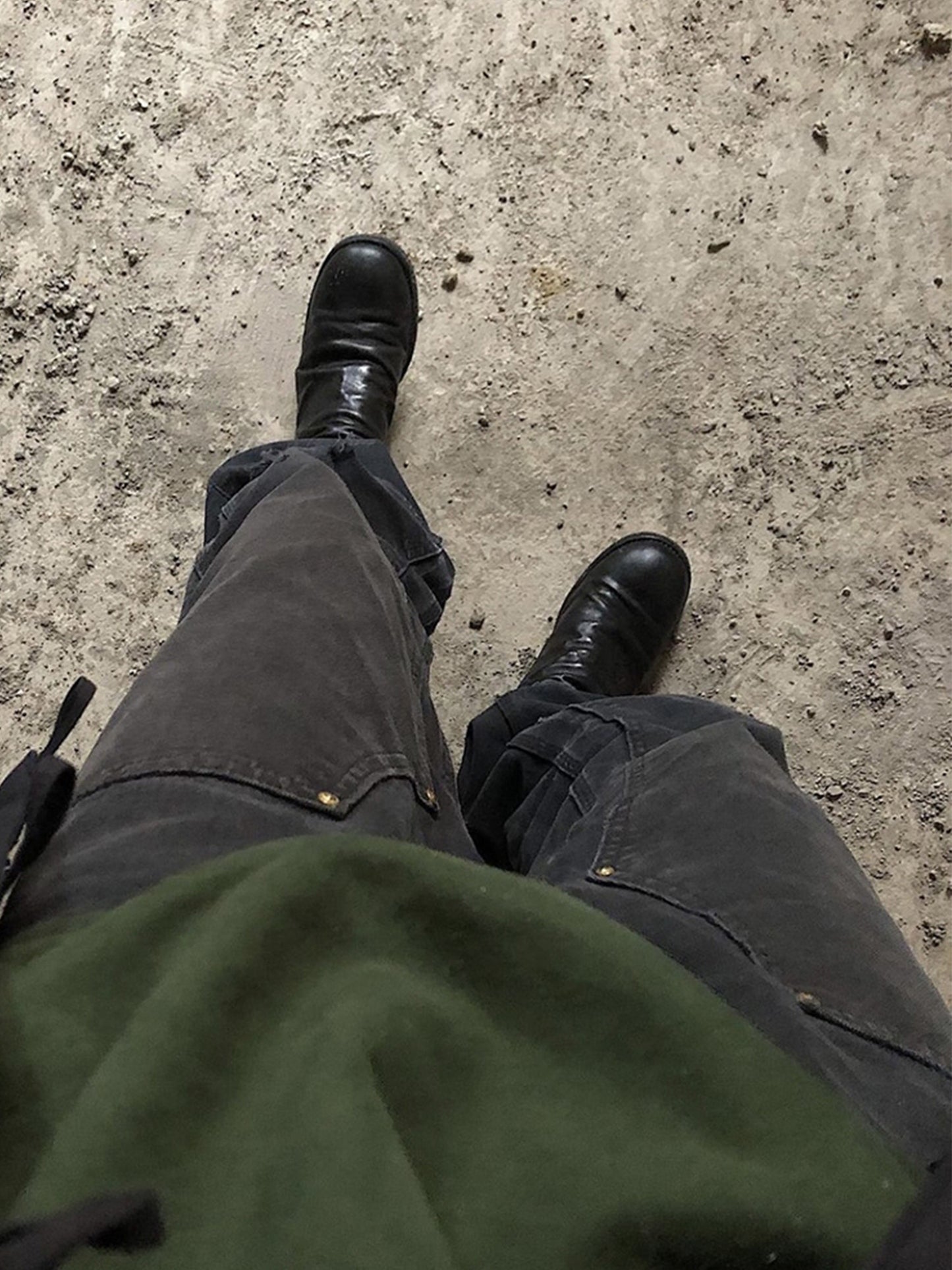 Person wearing black shoes and dark pants on a concrete surface