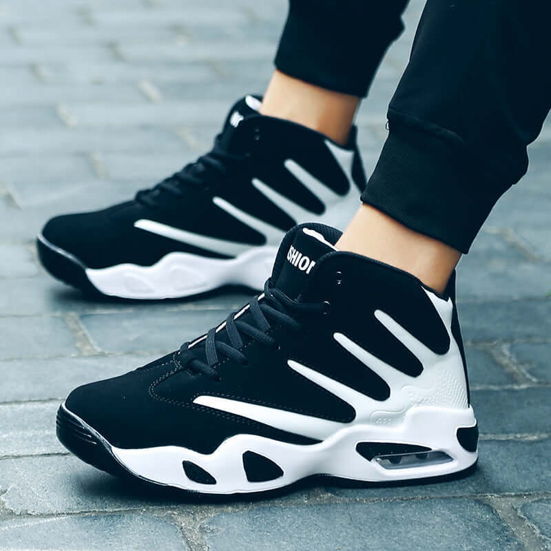 Black and white sneakers worn on a stone pavement