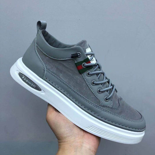 Gray sneaker with a brand logo held by a hand against a gray background