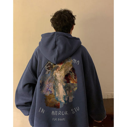 Person wearing a blue hoodie with an angel graphic on the back against a beige wall.