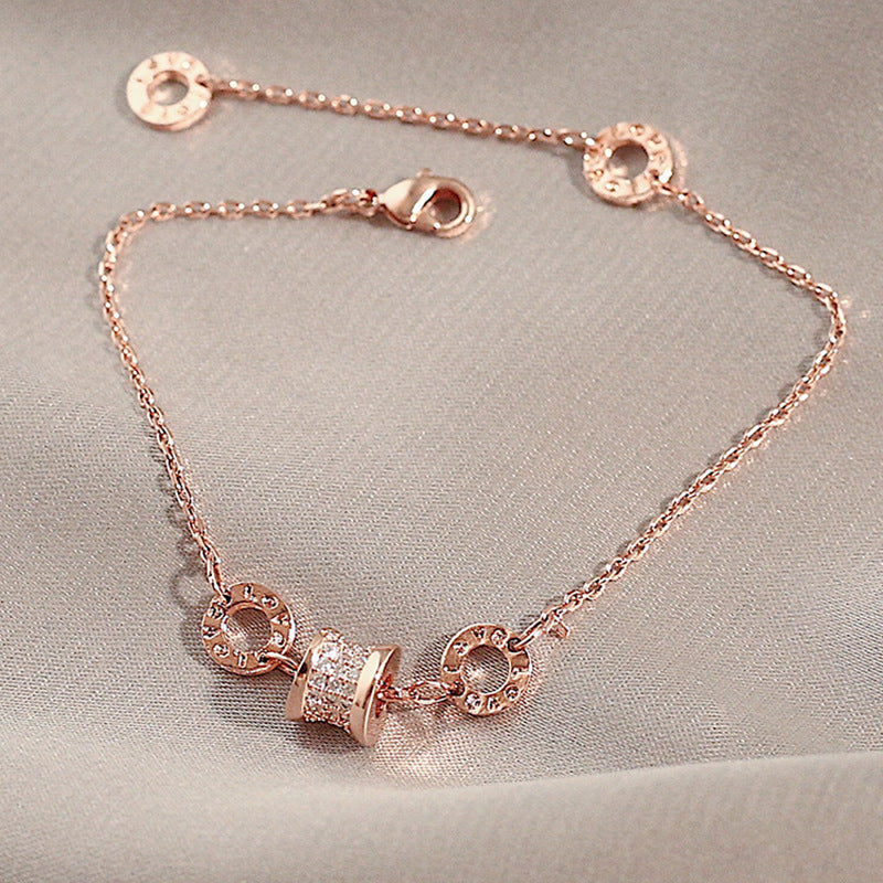Rose gold bracelet with circular charms on a light gray background