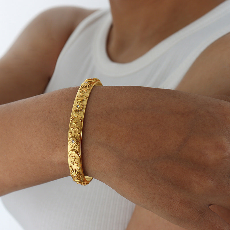 Gold bracelet on a wrist with a white background