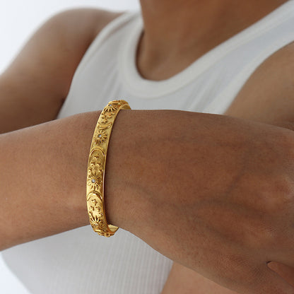 Gold bracelet on a wrist with a white background