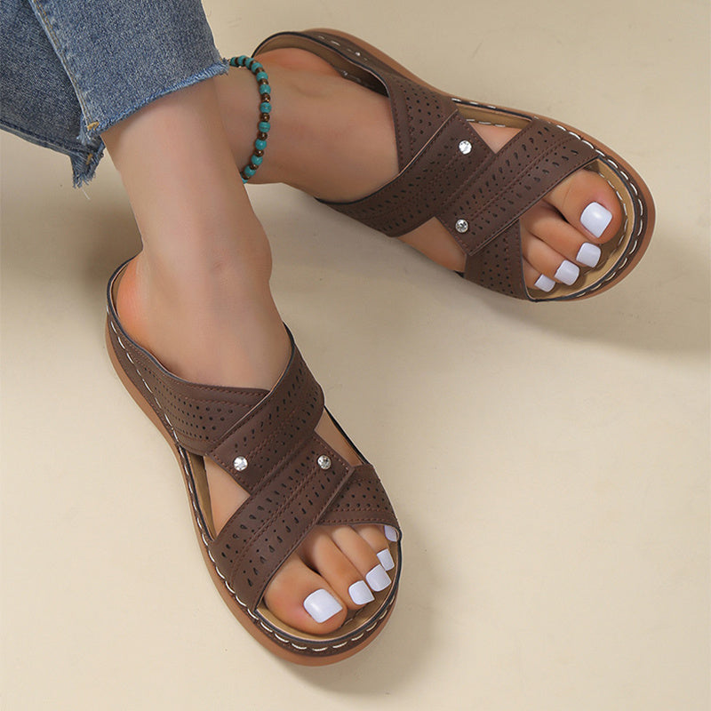 Brown sandals worn with denim jeans on a beige background