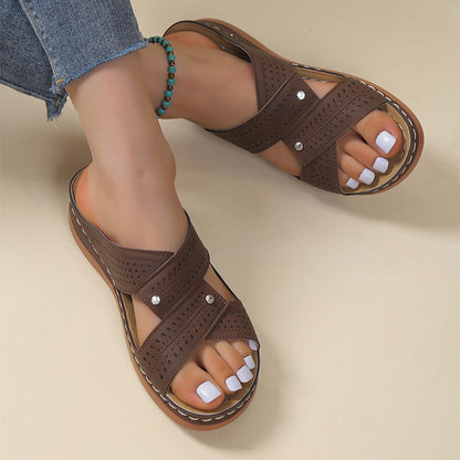 Brown sandals worn with denim jeans on a beige background