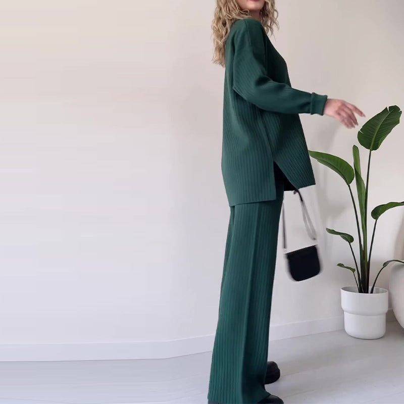 Person wearing a green outfit standing next to a potted plant indoors.