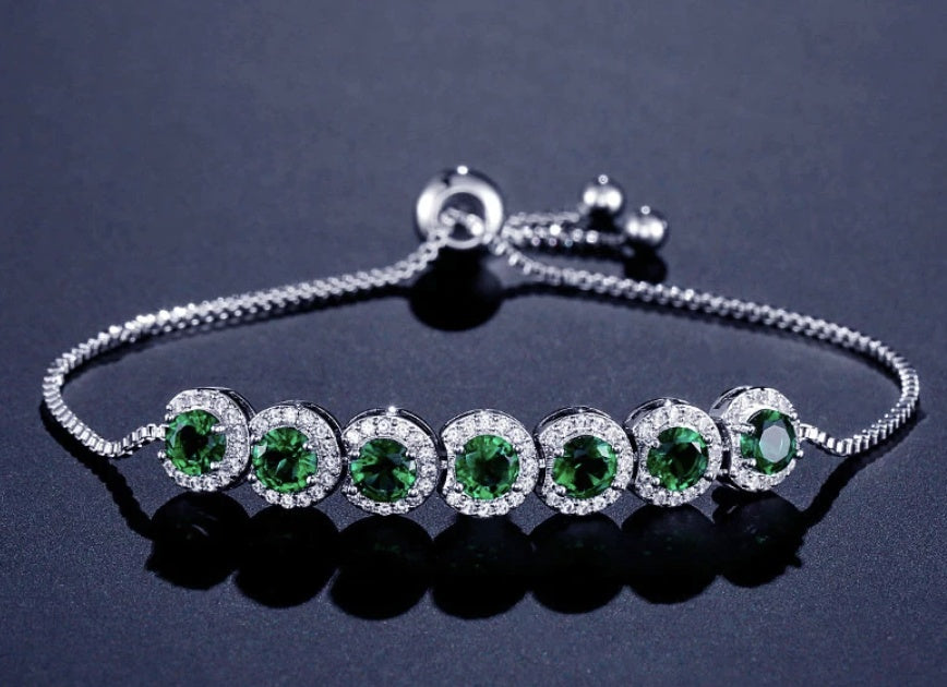 Silver bracelet with green gemstones on a dark background