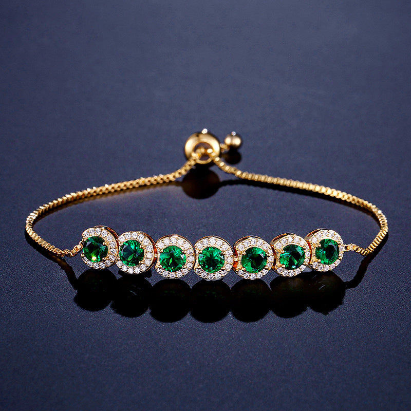 Gold bracelet with green gemstones on a dark blue background