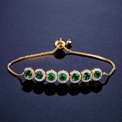 Gold bracelet with green gemstones on a dark blue background