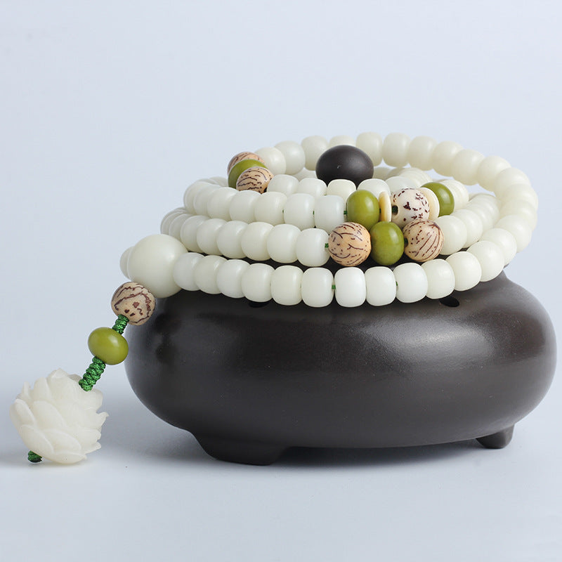 Stack of white and multicolored beaded bracelets on a dark brown pot against a light gray background