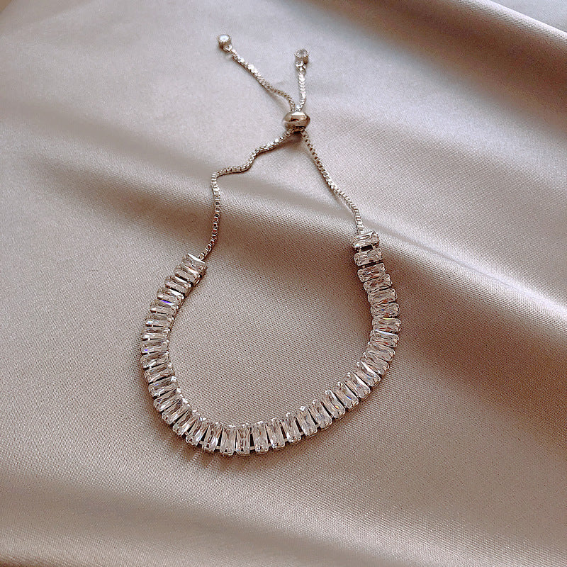 Silver beaded bracelet on a beige fabric background