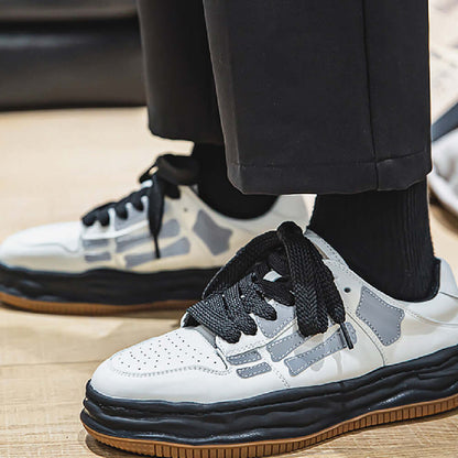 White sneakers with black and brown accents worn by a person on a wooden floor.