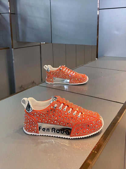 Orange sneakers with rhinestone details on a reflective surface