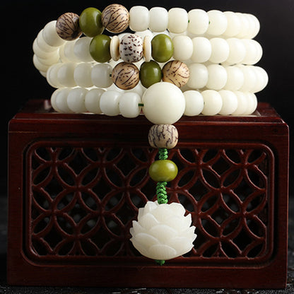 Stack of beaded bracelets with a decorative pendant on a wooden stand against a dark background