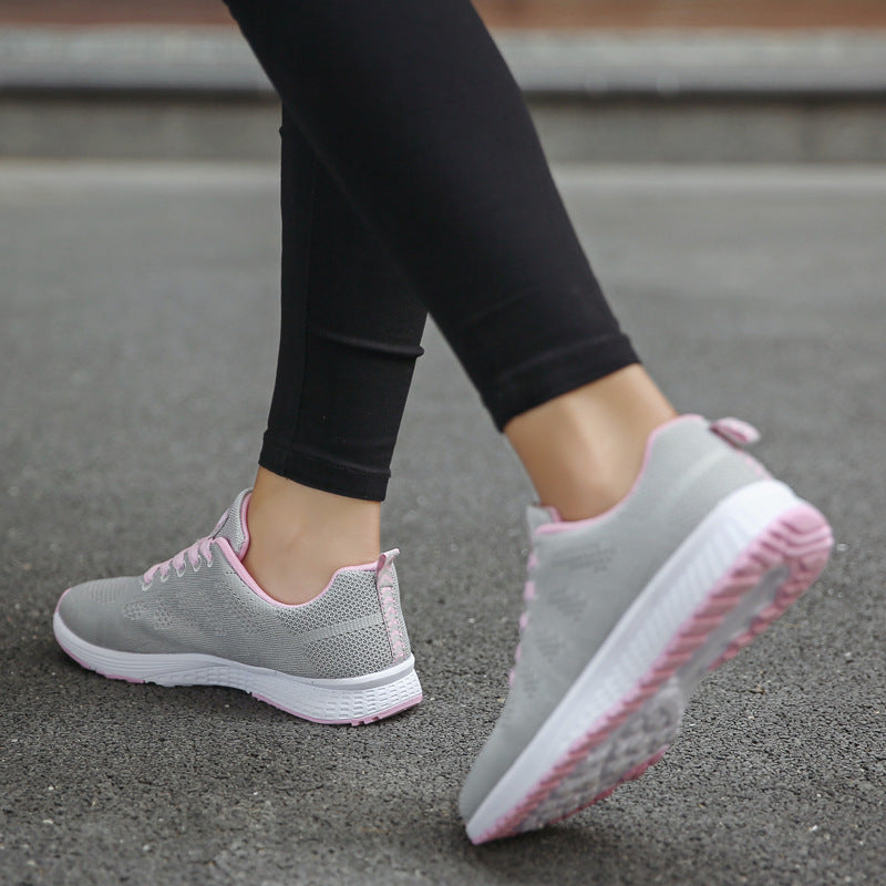 Gray sneakers with pink soles worn by a person on a concrete surface