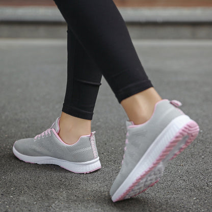 Gray sneakers with pink soles worn by a person on a concrete surface