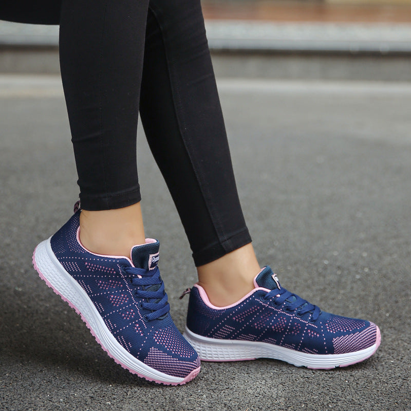Navy blue running shoes with pink accents worn by a person on a road.