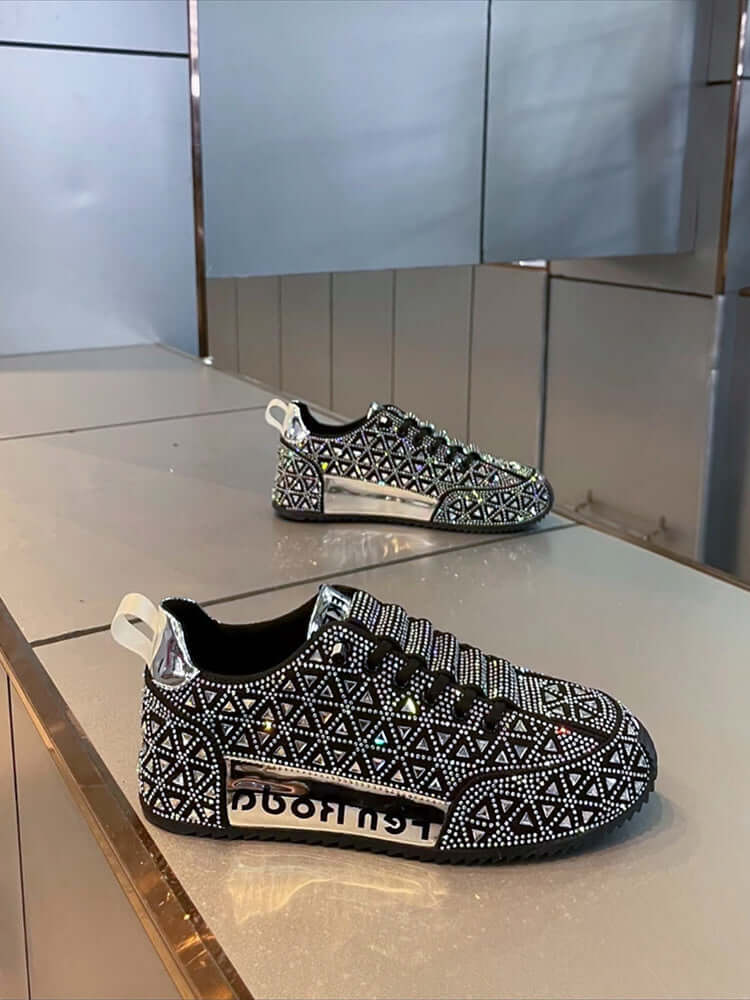 Black and white patterned sneakers with rhinestone embellishments on a reflective surface.