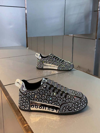 Black and white patterned sneakers with rhinestone embellishments on a reflective surface.